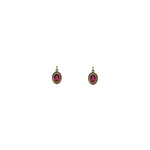 May include: A pair of gold earrings with oval-shaped red gemstones.