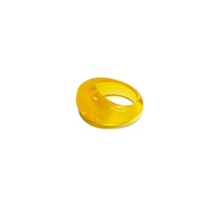 May include: A bright yellow resin ring with a rounded, slightly domed shape.
