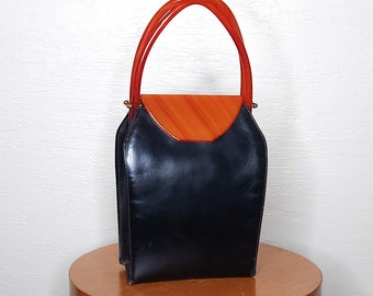 May include: A vintage black leather handbag with a top flap and a unique orange plastic handle.