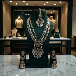 May include: An ornate gold-toned necklace set with pearl accents, displayed on a green velvet bust. The set includes a matching headpiece and earrings. The jewelry is intricately designed with a vintage aesthetic.