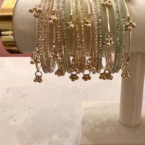 May include: A white ceramic mug with a black handle and the text "But First, Coffee" in a bold, black font. The mug is set against a blurred background, suggesting a cozy setting.