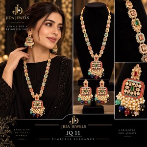 May include: A gold-toned jewelry set featuring a long necklace and matching square earrings. The pieces are adorned with multi-colored rectangular stones and clusters of small white, blue, and red beads. The Jida Jewels logo is visible.