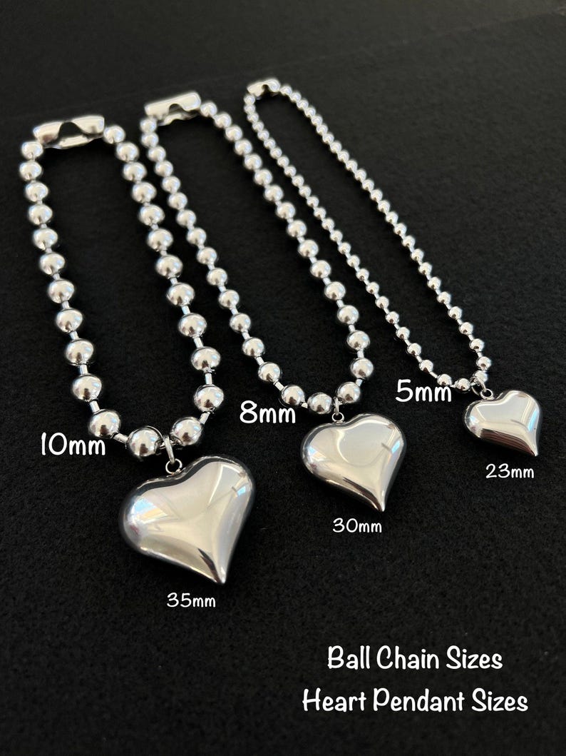 May include: Three silver ball chain necklaces with heart pendants. The chains are 10mm, 8mm, and 5mm in diameter. The heart pendants are 35mm, 30mm, and 23mm in size. Ball Chain Sizes Heart Pendant Sizes