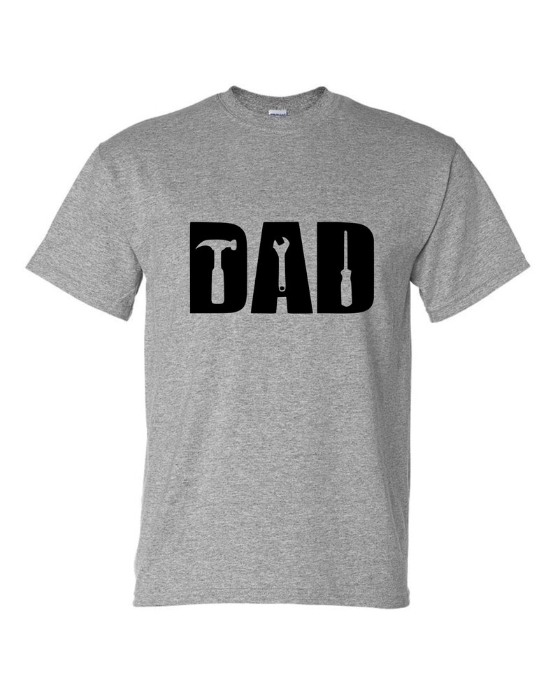 May include: Gray t-shirt with the word "DAD" in black letters. The letters are formed by a hammer, wrench, and screwdriver.