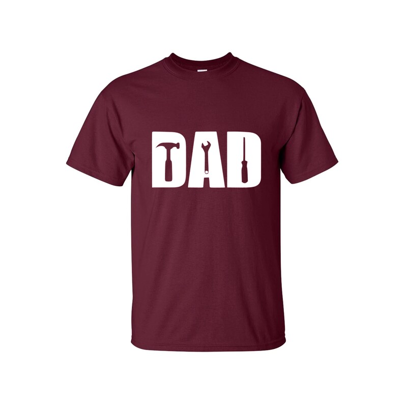 May include: Burgundy t-shirt with a white graphic of the word "DAD" with a hammer, wrench, and screwdriver replacing the letters.