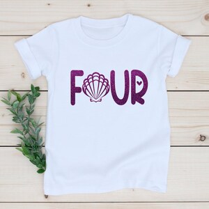 May include: White t-shirt with the word "FOUR" in purple glitter, featuring a seashell in the middle of the "O".