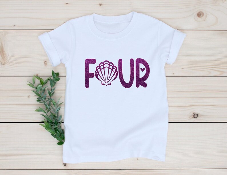 May include: White t-shirt with the word "FOUR" in purple glitter, featuring a seashell in the middle of the "O".