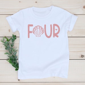 May include: White t-shirt with the word "FOUR" in pink glitter lettering. The letter "O" is replaced with a pink seashell graphic.