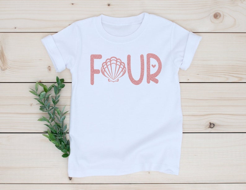 May include: White t-shirt with the word "FOUR" in pink glitter lettering. The letter "O" is replaced with a pink seashell graphic.