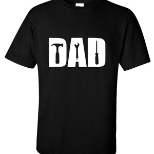May include: Black t-shirt with a white graphic of the word "DAD" with a hammer, wrench, and screwdriver replacing the letters.