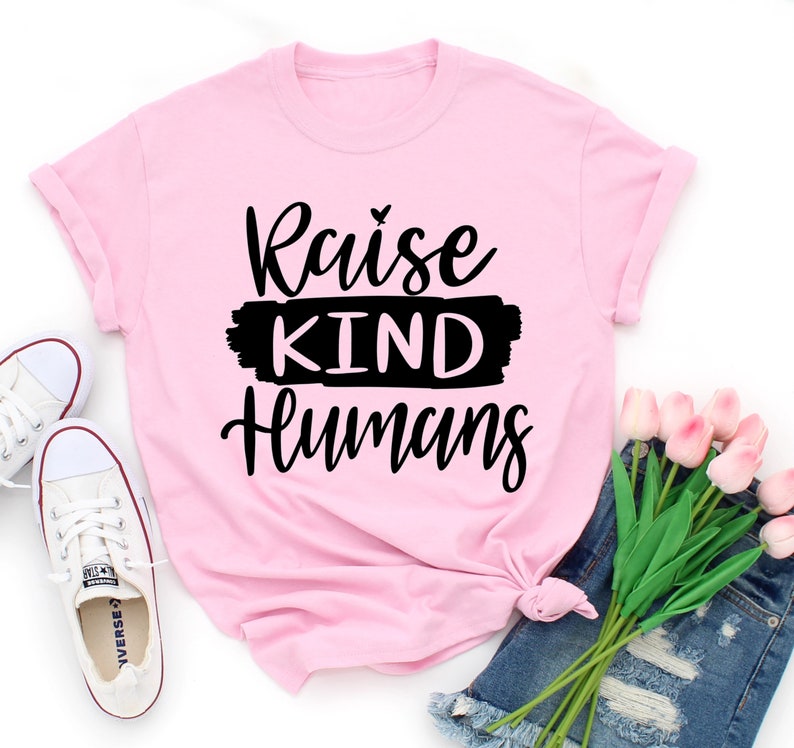 May include: Pink t-shirt with black text that reads "Raise Kind Humans".