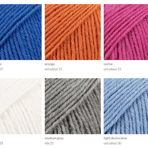 May include: Six skeins of yarn in different colors: bright blue, orange, cerise, white, medium grey, and light denim blue. The yarn is arranged in two rows of three skeins each.