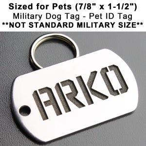 K&ouml;nnte beinhalten: Ein silberfarbener Hundemarkenanh&auml;nger aus Metall mit abgerundeter rechteckiger Form und einem daran befestigten Ring. Die Marke ist mit dem Text "&bull;ARKO" in einer fetten, klobigen Schrift graviert. Die Marke ist f&uuml;r Haustiere konzipiert und misst 7/8 Zoll mal 1 1/2 Zoll. **NOT STANDARD MILITARY SIZE**