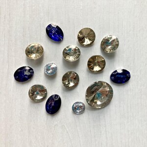 Op de afbeelding: Een assortiment sprankelende edelstenen in diverse vormen en maten, waaronder ovale en ronde slijpsels. De edelstenen hebben een reeks kleuren, waaronder helder, goud en diepblauw, gerangschikt op een lichtgekleurd oppervlak. Geschikt voor het maken van sieraden.