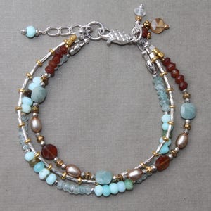May include: A multi-strand bracelet with a silver clasp and a variety of beads, including aquamarine, carnelian, and gold beads.