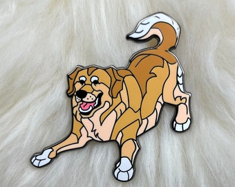 May include: An enamel pin featuring a cartoon dog in a playful pose, with its tongue sticking out. The dog is brown and white.