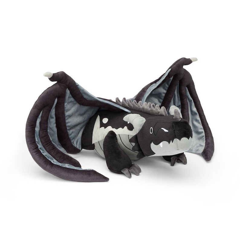May include: A plush dragon toy in black, gray, and white. The dragon has large wings, a long body, and a smiling face. The toy is made of soft material and is designed to be cuddled.