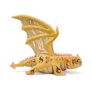May include: A plush golden dragon toy with large, shimmering wings. The dragon has intricate brown decorative patterns and orange accents on its claws and spine. The toy is designed to lay flat, showcasing its detailed design.