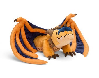Puede incluir: Un peluche de dragón en tonos naranja, azul y beige. El dragón tiene grandes alas con tela naranja en la parte delantera y azul oscuro en la trasera. El cuerpo del dragón es beige, con una cabeza azul y detalles marrones.