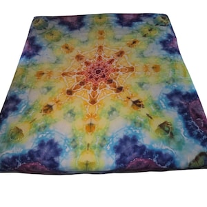 May include: A rectangular fabric tapestry featuring a tie-dye pattern with a central starburst design in shades of yellow, orange, and red, surrounded by swirling clouds of blue, purple, and green colors across the entire surface area.