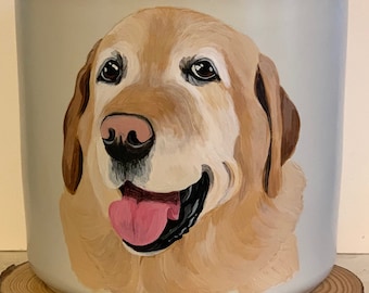 May include: A ceramic canister with a wooden lid, featuring a hand-painted portrait of a golden retriever dog. The dog has a light brown coat, a pink tongue, and a friendly expression.