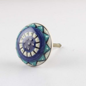 May include: A blue and green ceramic knob with a mandala design. The knob has a white background and a silver screw.