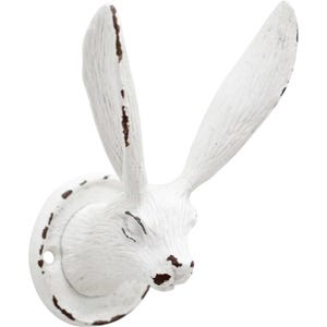 Può includere: Gancio da parete in metallo bianco a forma di testa di coniglio. Il gancio ha un aspetto invecchiato e vintage con dettagli marroni. Le orecchie del coniglio sono dritte e il gancio è montato su una base circolare con un foro per la vite.