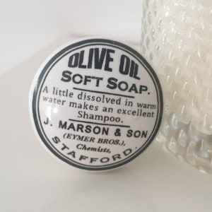 May include: A white ceramic jar lid with black lettering that reads "Olive Oil Soft Soap. A little dissolved in warm water makes an excellent Shampoo. J. Marson & Son (Eymer Bros.), Chemists, Stafford."
