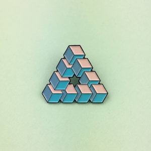 Könnte beinhalten: Geometrischer Ansteckpin in Form eines Dreiecks, bestehend aus gestapelten Würfeln. Die Würfel wechseln sich in Hellblau und Pfirsich ab, umrandet in Schwarz. Der Pin befindet sich vor einem hellgrünen Hintergrund.