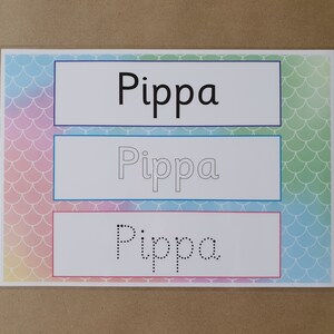 May include: A learning aid featuring the name "Pippa" in three different styles. The top section displays the name in a bold, black font. The middle section shows the name as an outline, and the bottom section presents the name as dotted lines for tracing. The background has a mermaid scale pattern.