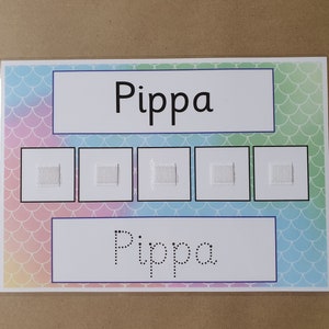 May include: A laminated educational chart with the name "Pippa" in large, bold letters at the top and bottom. The background features a pastel mermaid scale pattern. Five small squares with textured patches are in the center.