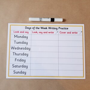 May include: A white and yellow educational worksheet for practicing writing the days of the week, with the text "Days of the Week Writing Practice." A white marker with black accents rests above the worksheet.