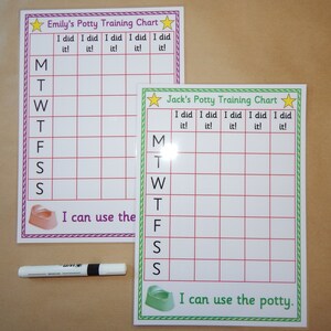 May include: Two potty training charts, one with a purple border and one with a green border, featuring grids for tracking progress. The charts are labelled "Emily's" and "Jack's". The phrase "I can use the potty" is at the bottom. A white marker is also present.