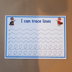 May include: A white educational tracing worksheet with a blue border. The text "I can trace lines" is at the top. The worksheet features dotted lines in various patterns, including zigzags and loops, for tracing practice. Superhero illustrations are on each side of the text.