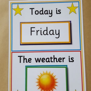 May include: A laminated educational poster with the text "Today is Friday" and "The weather is" with a sun illustration. The poster has a white background with colorful borders and yellow star accents.