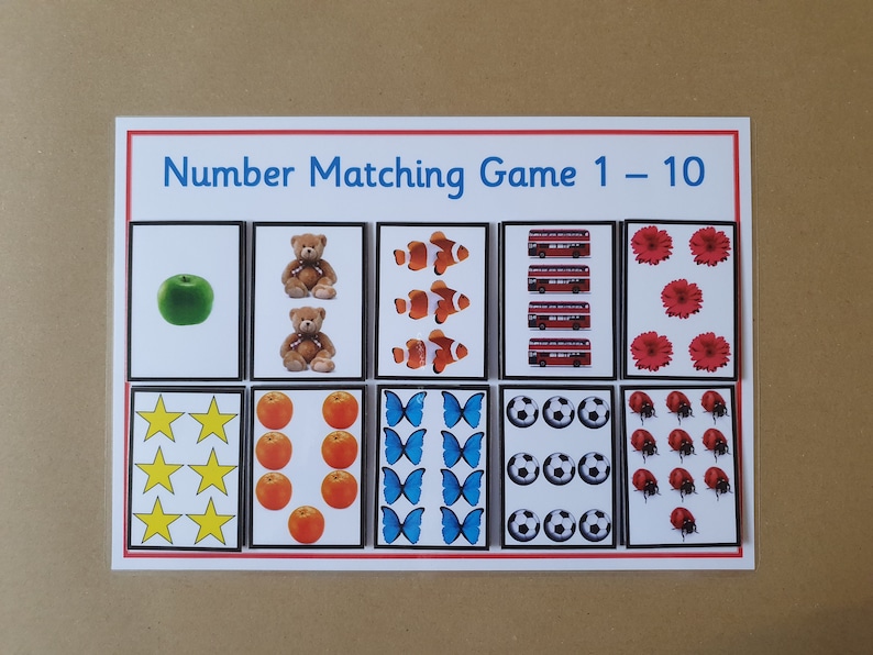 May include: A number matching game with the title "Number Matching Game 1-10". The game features cards with images of apples, teddy bears, clownfish, red buses, flowers, stars, oranges, butterflies, soccer balls, and ladybugs.