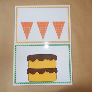 May include: Two illustrated cards. The top card features three orange ice cream cones. The bottom card shows a two-layer yellow cake with chocolate frosting. Both cards have decorative borders.