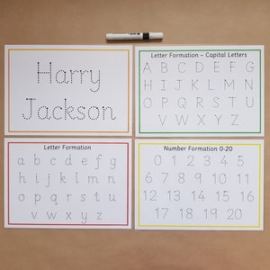 May include: Educational handwriting practice set with four white cards. The cards feature dotted lines for tracing capital and lowercase letters, numbers 0-20, and a name card. A black marker is included.