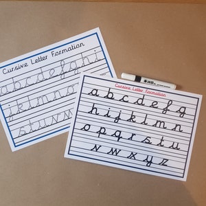 May include: Two white rectangular educational worksheets titled Cursive Letter Formation with black lines and letters. One sheet features dotted letters for tracing, while the other shows solid cursive letters. A white dry-erase marker is included.