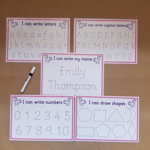 May include: Educational learning set with five white cards featuring pink borders and unicorn graphics. The cards include tracing activities for letters, capital letters, numbers, shapes, and a name. A black and white marker is included.