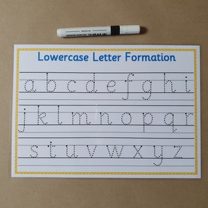 May include: A handwriting practice chart with the words "Lowercase Letter Formation" in blue. The chart features dotted lowercase letters. A white marker with a black band is above the chart. The background is tan.