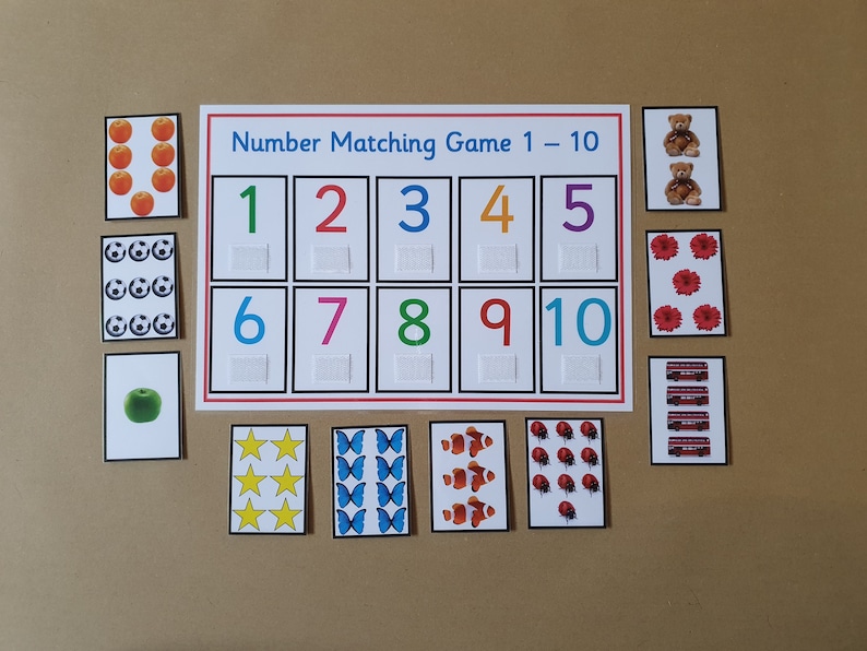 May include: A number matching game with cards featuring colorful numbers 1-10 and corresponding images like apples, soccer balls, and teddy bears. The game includes a white board with the text "Number Matching Game 1-10".