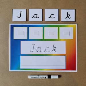 May include: A laminated educational activity sheet with a rainbow gradient background featuring the name Jack in dotted cursive font, four white squares with velcro strips, a blank writing line, four separate letter tiles, and a white dry erase marker.