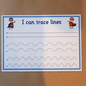May include: A white tracing worksheet with blue borders and the text "I can trace lines." The worksheet features dotted lines in various patterns, with superhero illustrations at the top. Great for early childhood education and fine motor skills.