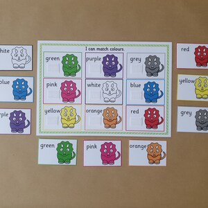 May include: A colour matching game featuring dinosaur illustrations. The game includes a central board with colour-coded dinosaur images and matching cards. Text on the board reads "I can match colours."