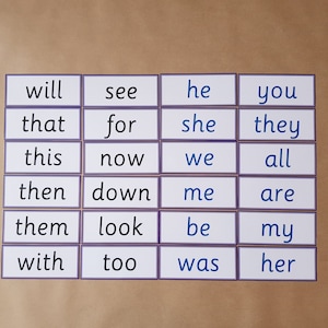 May include: A collection of flashcards with sight words, including "will," "see," "he," and "you." Each card has a white background with a purple border and black text. The cards are arranged on a light brown surface.
