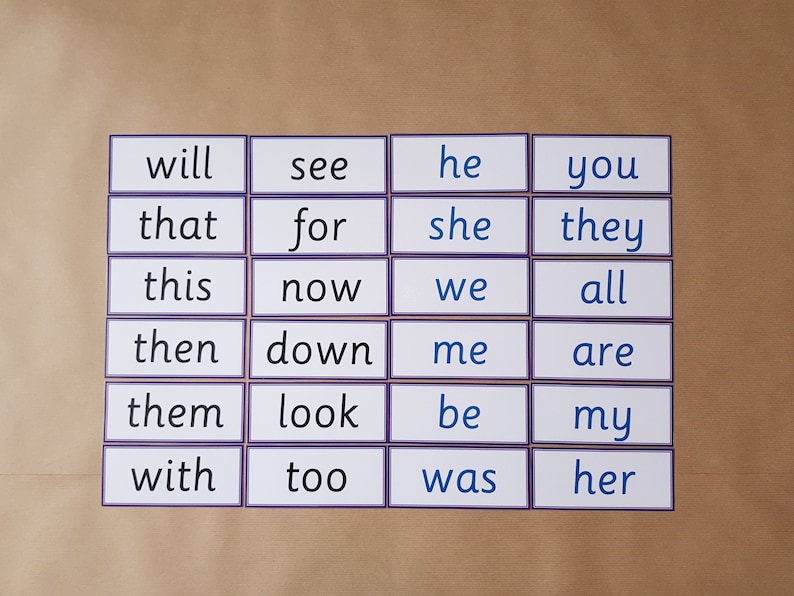 May include: A collection of flashcards with sight words, including "will," "see," "he," and "you." Each card has a white background with a purple border and black text. The cards are arranged on a light brown surface.