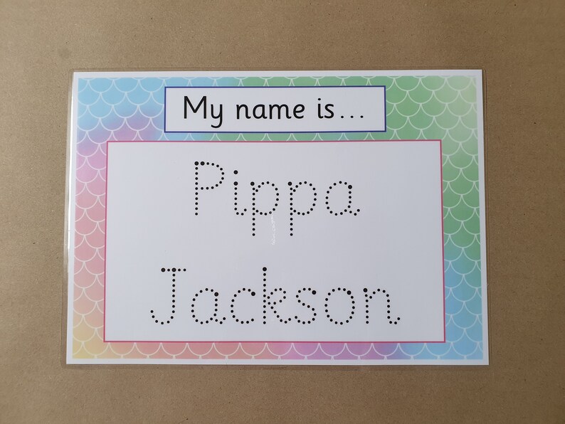 May include: A name tag with a colorful mermaid scale border. The tag has the text "My name is..." in a blue box, and the name "Pippa Jackson" in dotted letters for tracing.