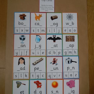 May include: Educational clip cards for learning missing letters. The cards feature colourful illustrations of objects and animals, with missing letters to be filled in. The text "Missing Letters Clip Cards" is at the top.