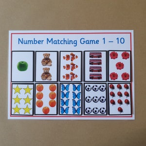 May include: A number matching game for children, featuring cards with illustrations of objects representing numbers 1-10. Includes a green apple, teddy bears, clownfish, red buses, flowers, stars, oranges, butterflies, soccer balls, and ladybugs.